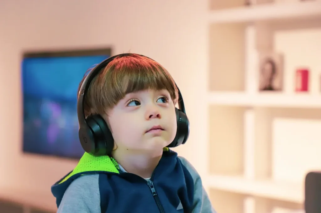 A young boy wearing headphones looking up.