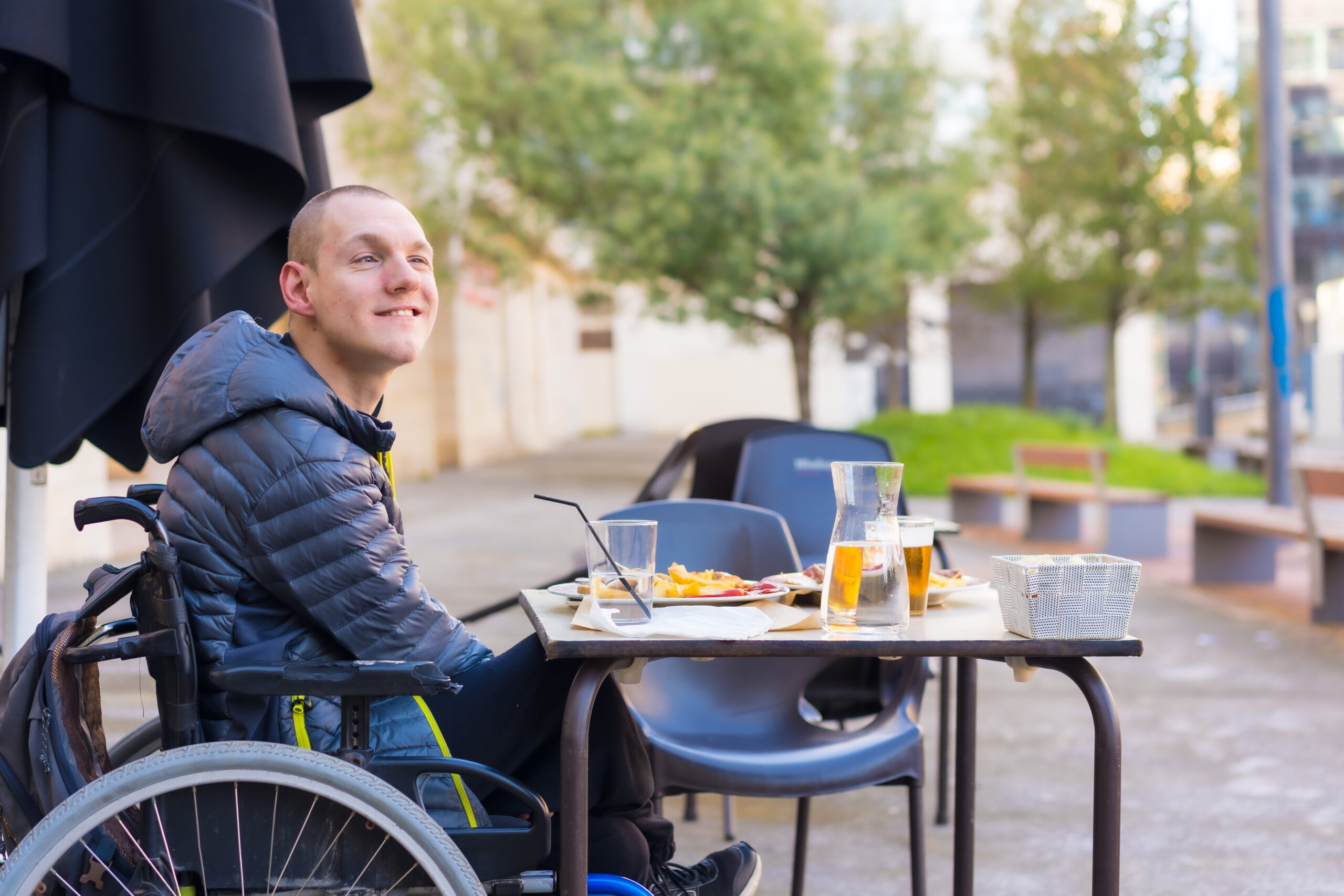 A man in a wheelchair at an outdoor table with food.