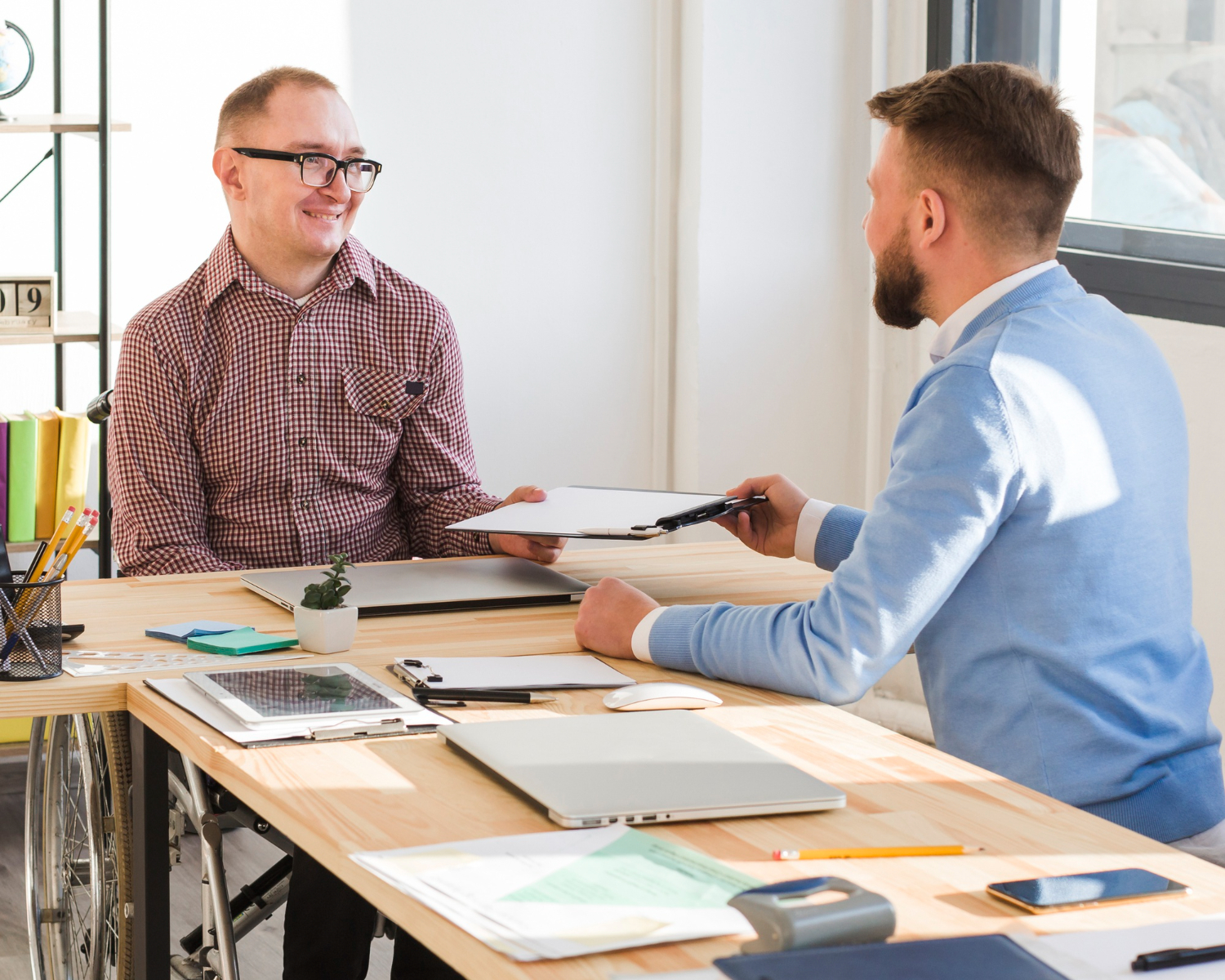 Two men sitting at a table talking to each other.