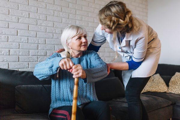 A woman helping an older person with a cane