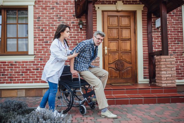 A woman pushing an older man in a wheelchair.